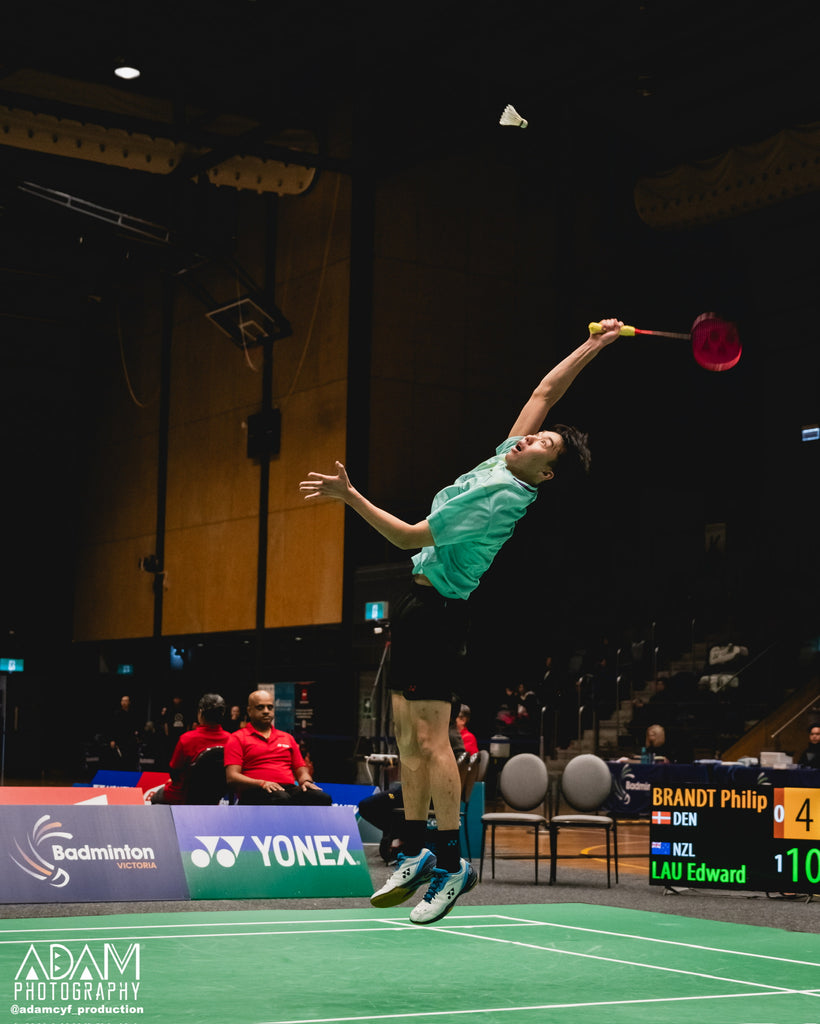 Male badminton player reaching for shot