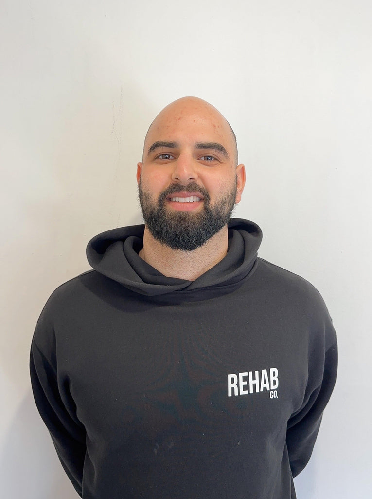 Man wearing a black hoodie with 'REHAB' text against a white background